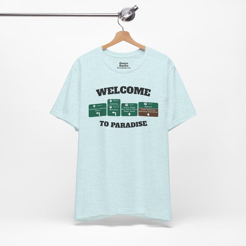 Light blue heather t-shirt with WELCOME TO PARADISE lettering and a row of green Outer Banks highway signs across the chest